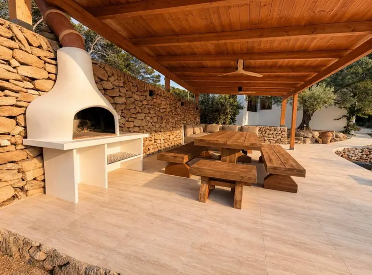 Barbacoa de obra blanca junto a un muro de piedra seca